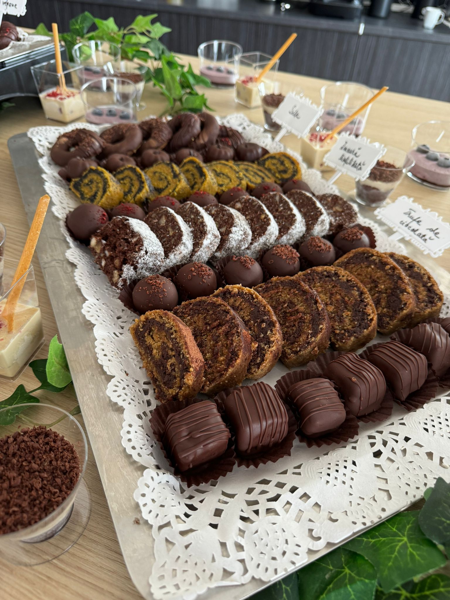 Platou cu prăjituri vegane fără zahăr, gluten, lactate sau ou: rulade cu mac, bomboane raw vegane cu ciocolată și cocos, trufe și mousse-uri fără coacere, servite elegant pentru evenimente.