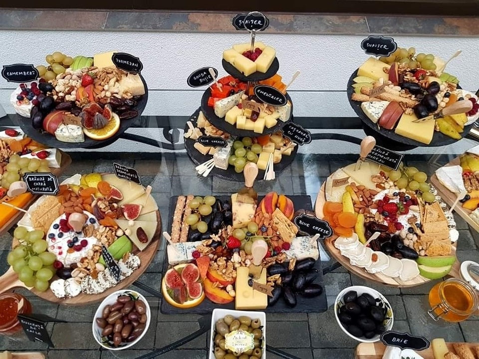 Prezentare completă Cheese Bar cu platouri de brânzeturi variate – brie, camembert, parmezan, blue cheese, gouda –, alături de struguri, nuci, smochine, caise uscate, biscuiți și etichete personalizate.