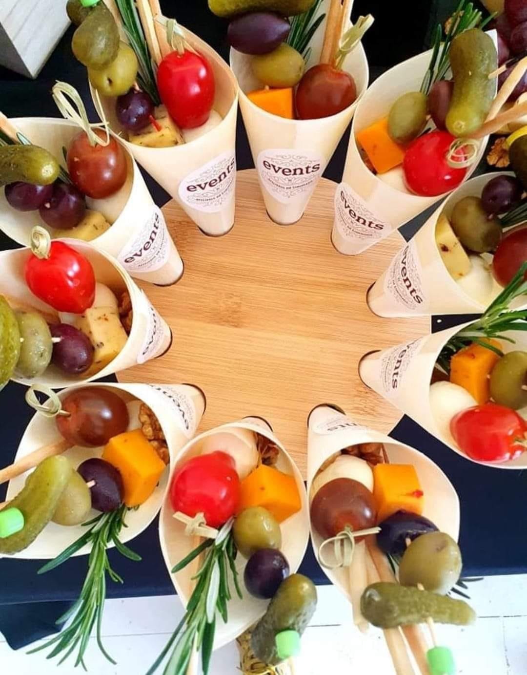 Conuri individuale pentru Cheese Bar, umplute cu brânzeturi, măsline, roșii cherry, murături și grisine, așezate circular pentru servire ușoară.