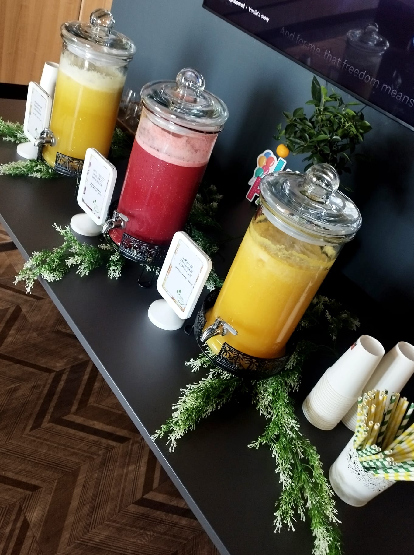 Prim-plan cu dispensere de limonadă și smoothie de ananas și fructe de pădure, servite la un eveniment. Băuturi răcoritoare 100% naturale. | Atelierul de Limonadă