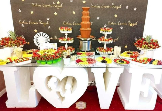 Fruit bar cu fântână de ciocolată belgiană și aranjamente spectaculoase din fructe proaspete, decorat cu litere volumetrice LOVE pentru un eveniment elegant.