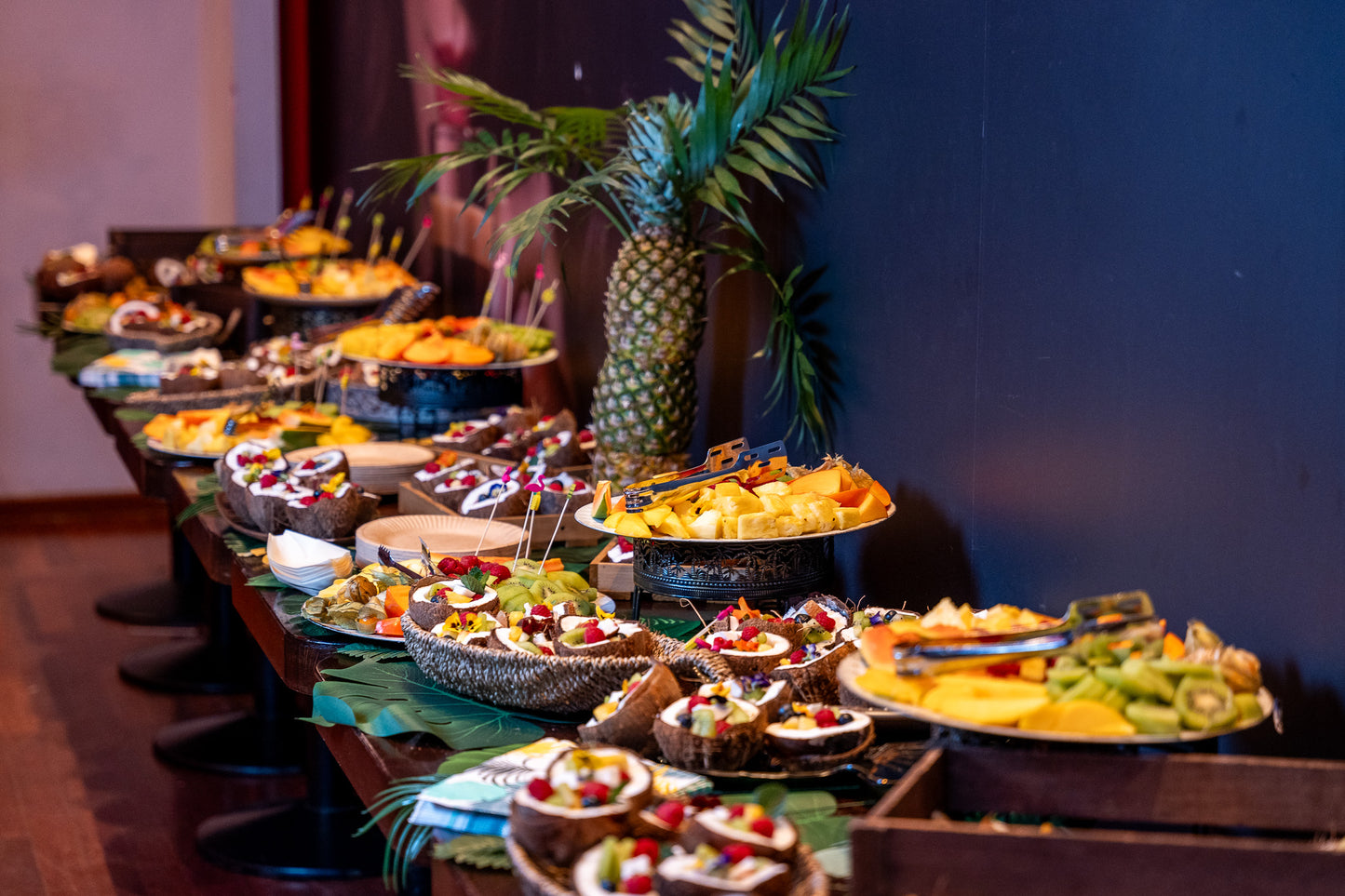 Fruit bar cu decor tropical și prezentare exotică în jumătăți de cocos, cu ananas, kiwi, fructe de pădure și flori comestibile.