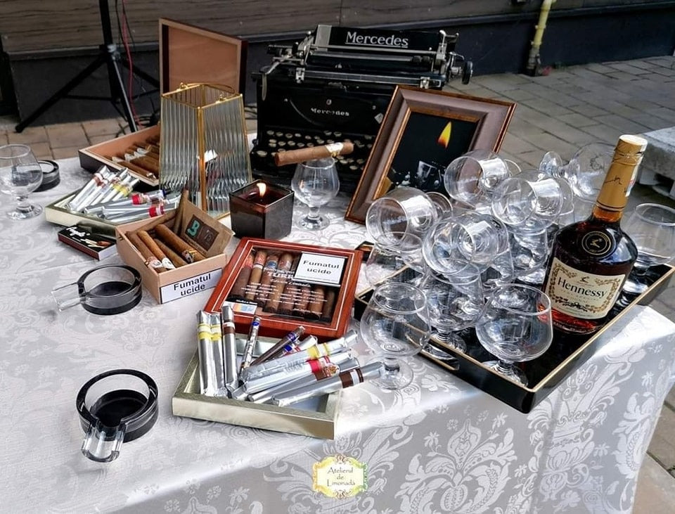 Setup elegant de cigar bar cu trabucuri, cognac Hennessy, pahare de degustare și decor vintage pentru evenimente rafinate.