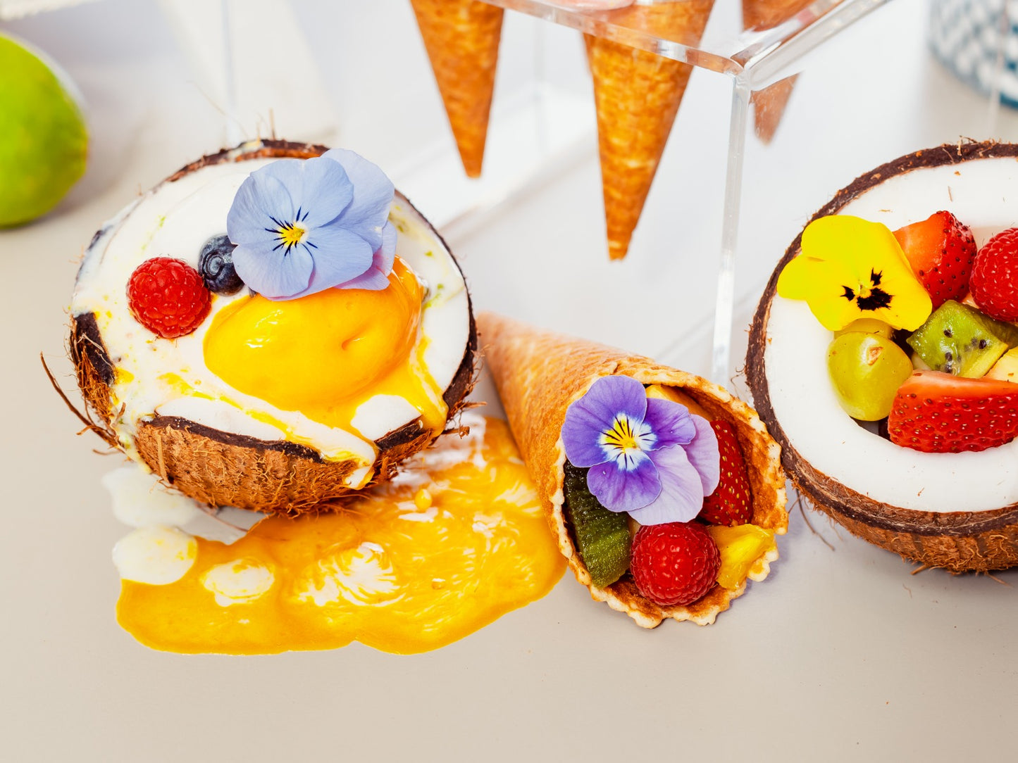 Desert artizanal servit în coajă de cocos și cornet, decorat cu fructe și flori comestibile, din oferta Gelato Bar – ice cream bar pentru evenimente.