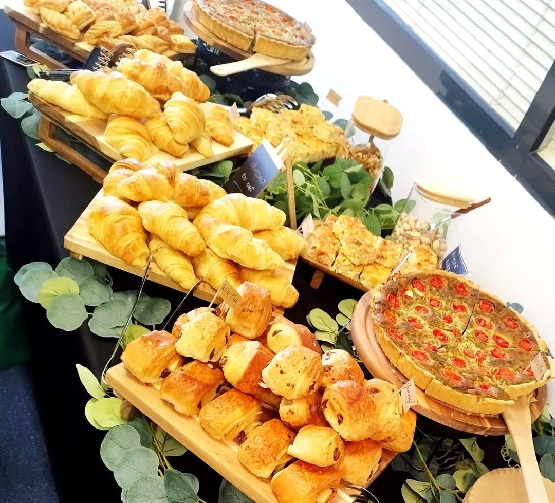 Bufet de brunch pentru evenimente corporate, cu o selecție de patiserie proaspătă, incluzând pateuri cu ciocolată, croissante și quiche-uri sărate.