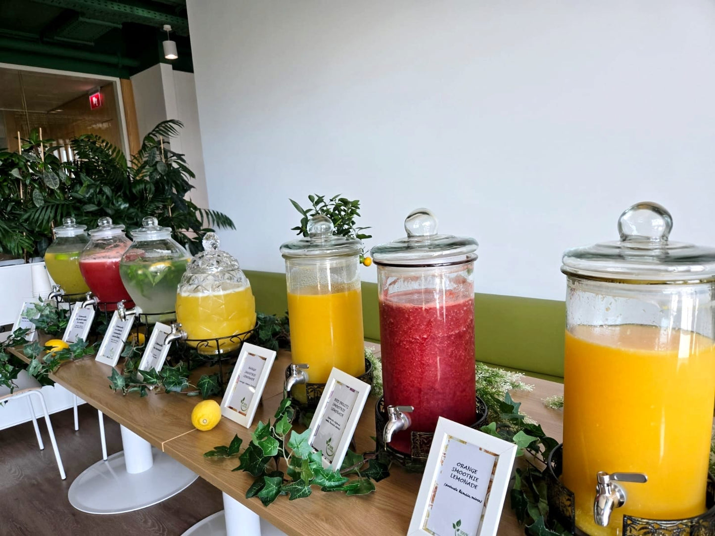 Bar de limonadă și smoothie pentru evenimente corporate, cu dispensere de sticlă pline cu băuturi naturale și colorate, decorat cu lămâi proaspete. | Atelierul de Limonadă