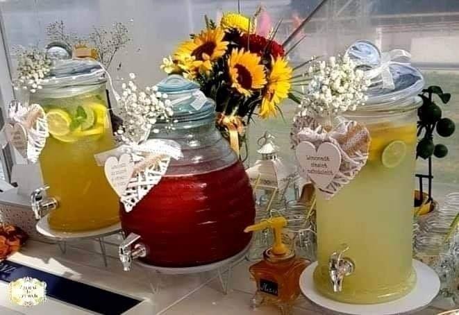 Stand de limonadă decorat cu flori, conținând limonadă clasică cu miere, mix de fructe roșii și limonadă cu lămâie și lime