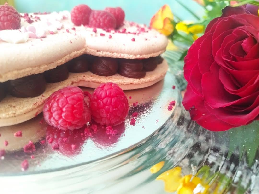 Tort macaron în formă de inimă, cu ganache de ciocolată și zmeură proaspătă, un desert special pentru o aniversare romantică.