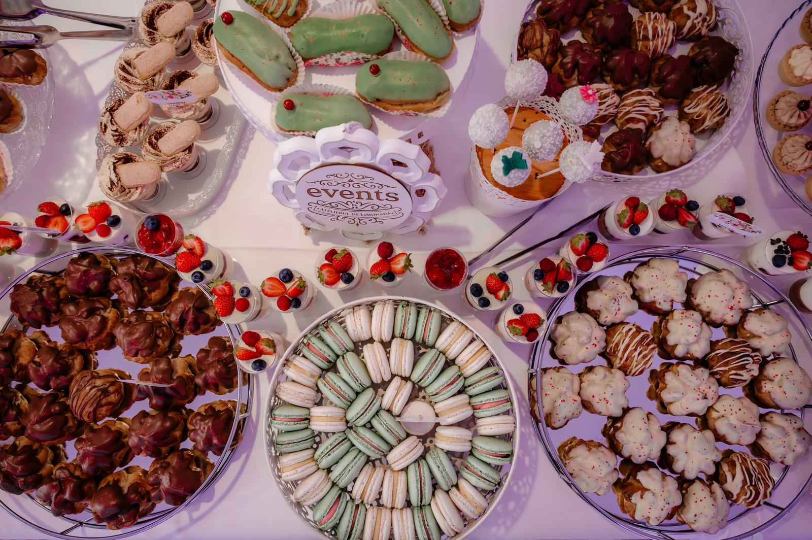 Candy bar cu macarons, eclere glazurate, deserturi cu fructe și prăjituri elegante, pregătit de Atelierul de Limonadă pentru evenimente speciale.