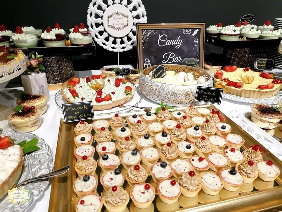 Prezentare candy bar cu mini tarte, macarons și prăjituri elegante, pregătite de Atelierul de Limonadă pentru un eveniment special.