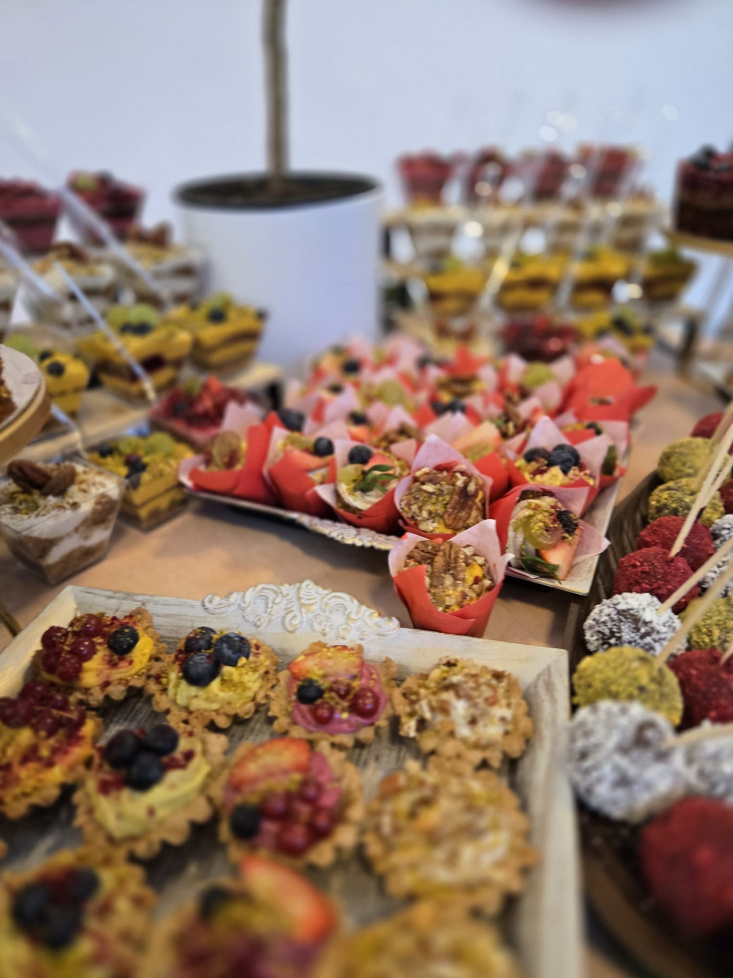 Bufet cu deserturi vegane asortate: mini tarte cu fructe de pădure, brioșe și trufe raw-vegane, ideale pentru un candy bar sănătos la evenimente.