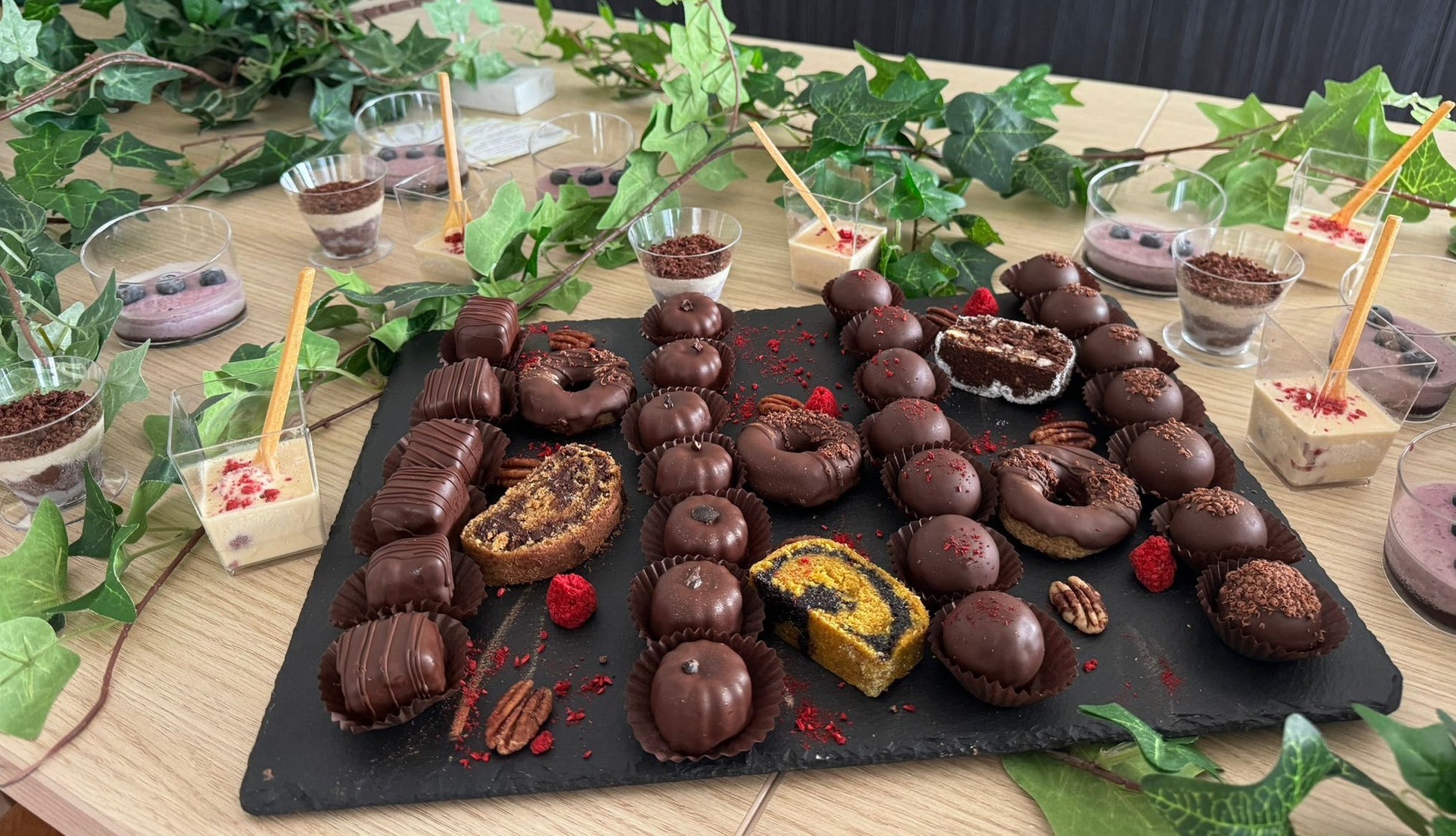 Prăjituri vegane fără zahăr, gluten, lactate sau ou, decorate cu ciocolată și servite pe platou cu mousse-uri naturale, în stil candy bar.