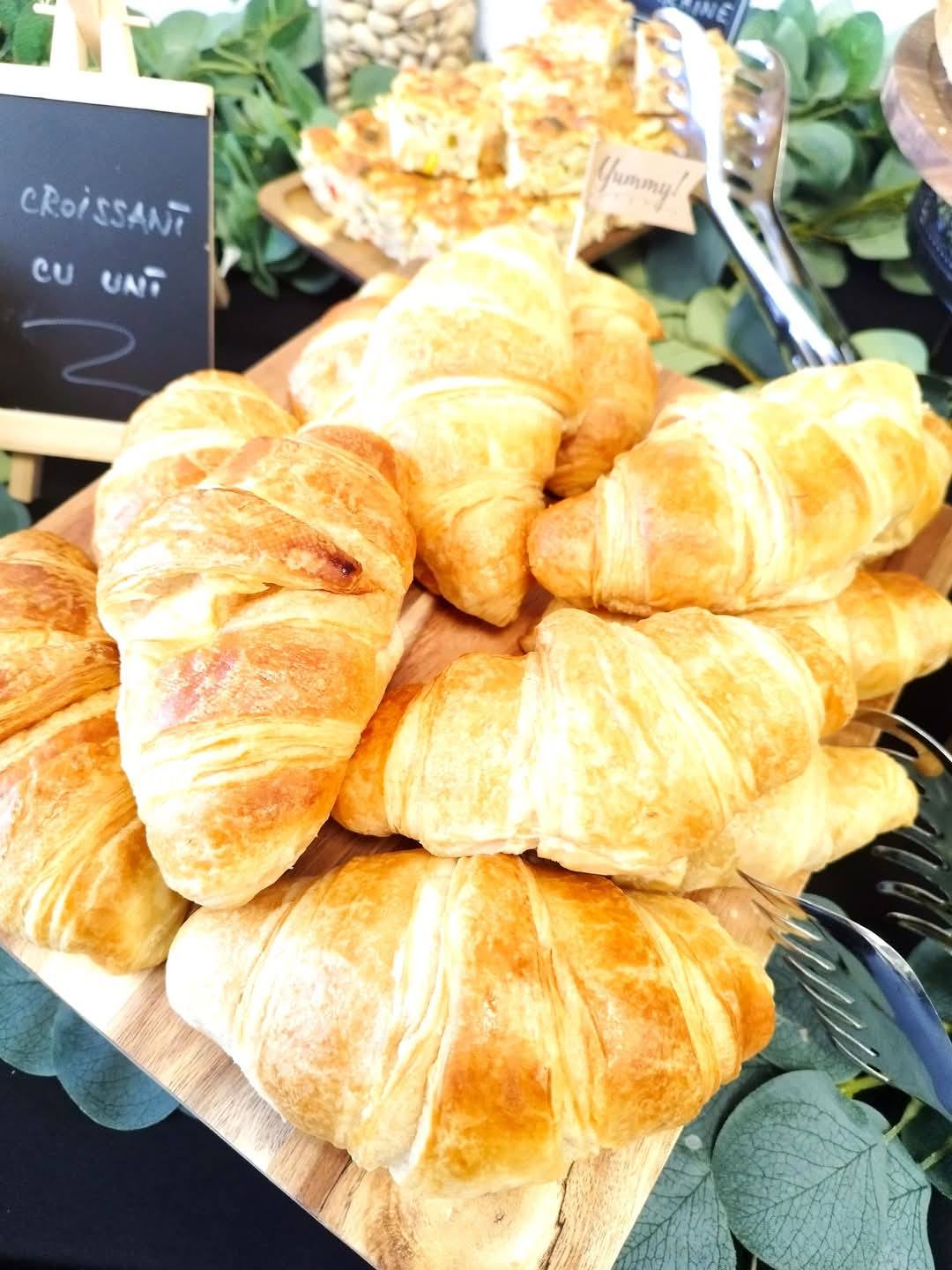 Platou cu croissante proaspete cu unt, parte din meniul de mic dejun pentru evenimente corporate.