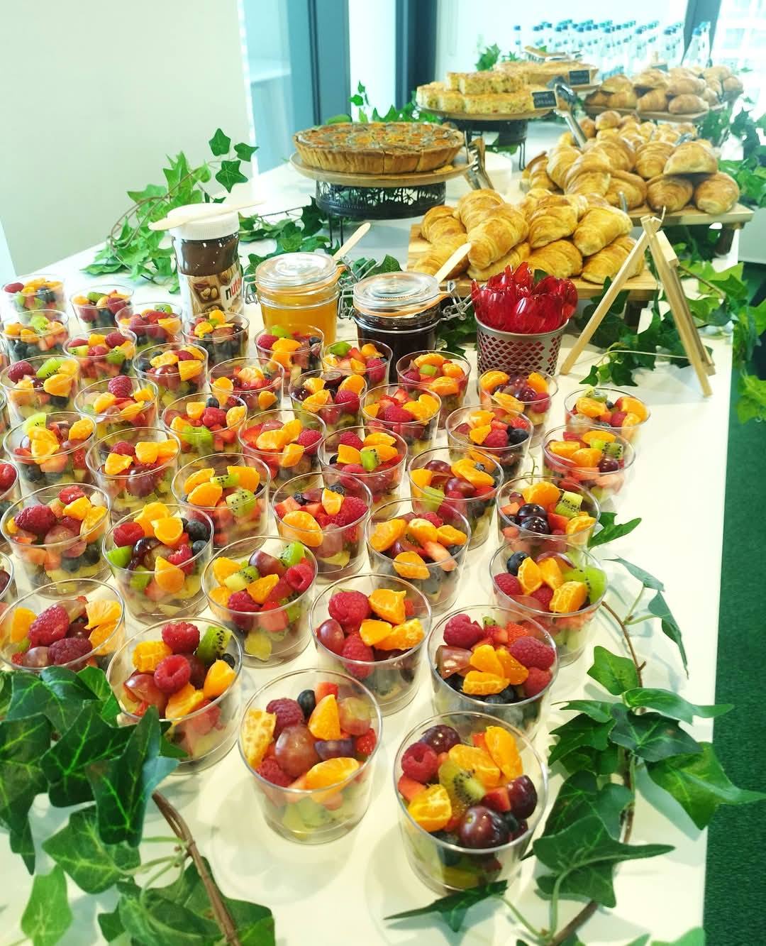 Bufet de mic dejun sănătos pentru evenimente corporate, cu salate de fructe proaspete la pahar, croissante și tarte.