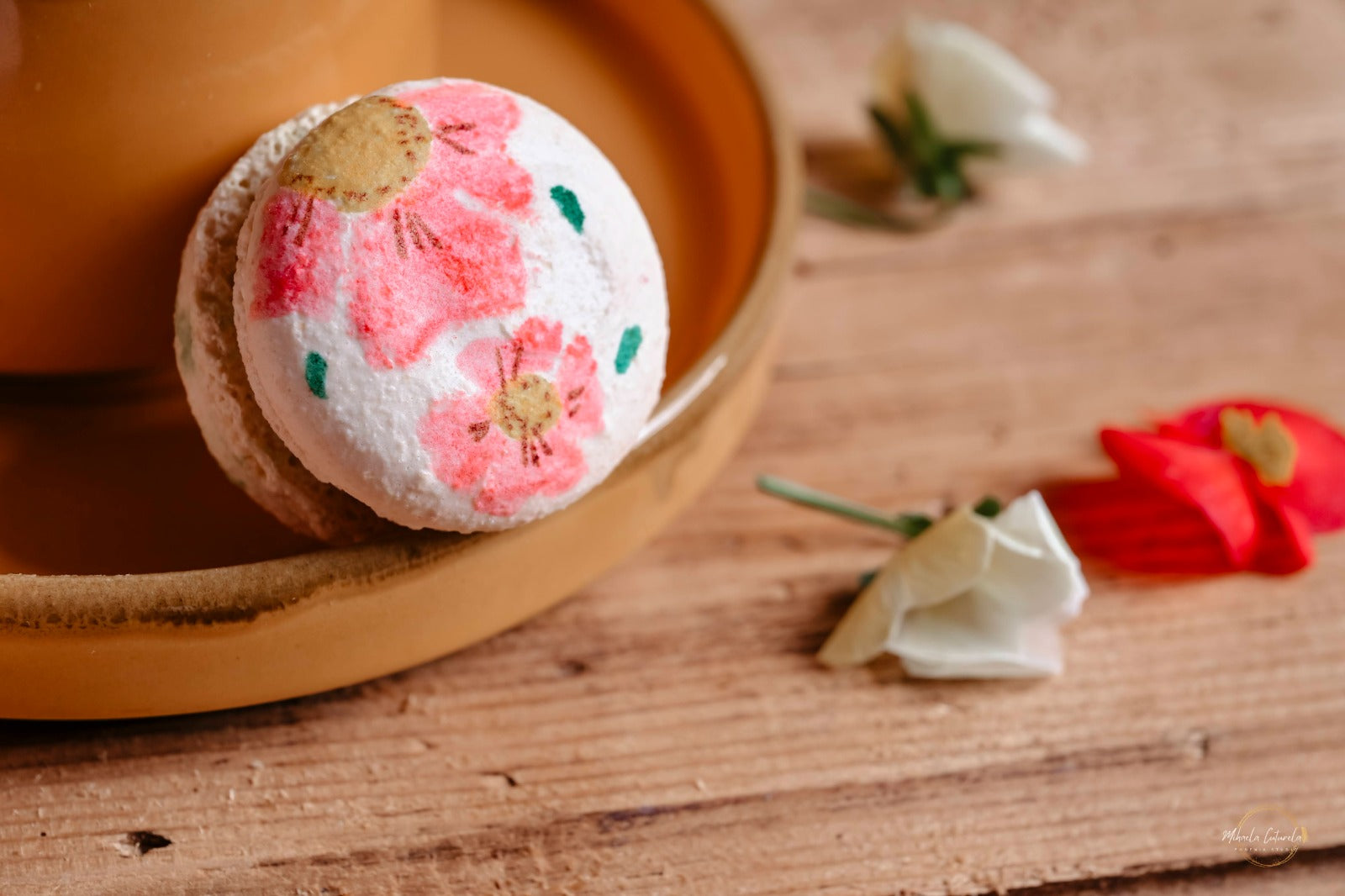 Close-up cu un macaron artizanal pictat manual cu flori roz delicate, un detaliu artistic. Marturii dulci.