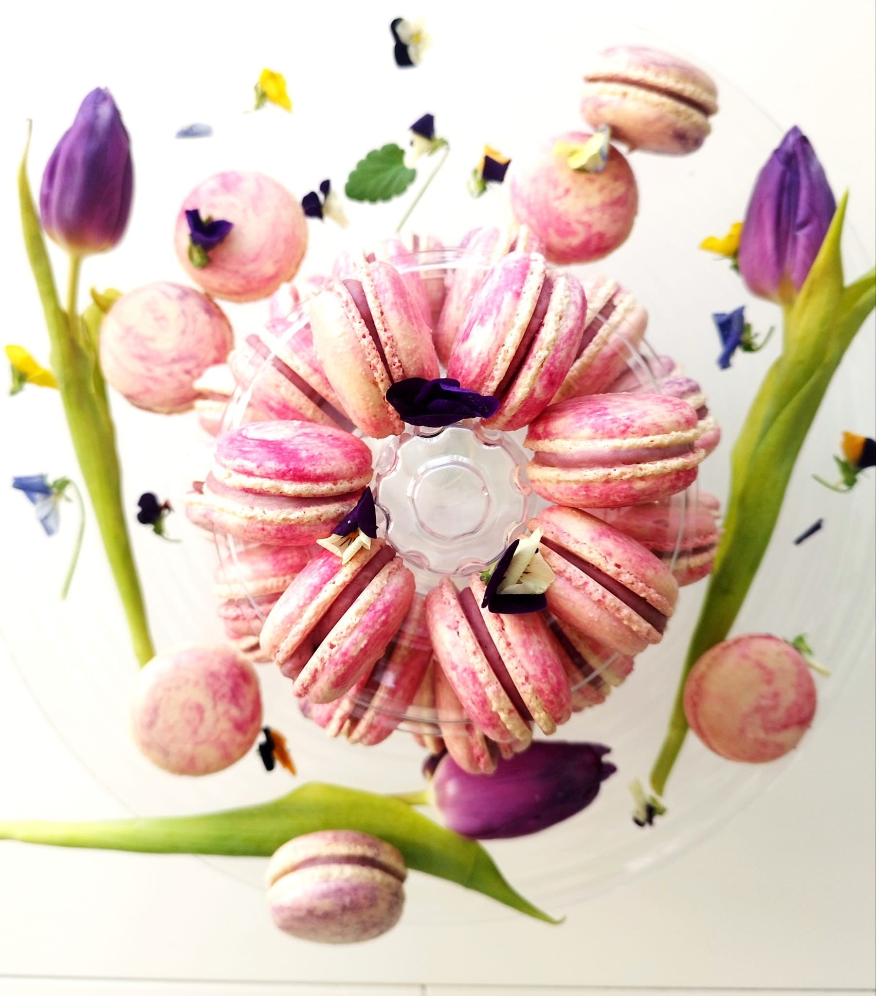 Aranjament artistic cu macarons roz marmorat, lalele mov și panseluțe, un cadou dulce și elegant pentru ocazii speciale.