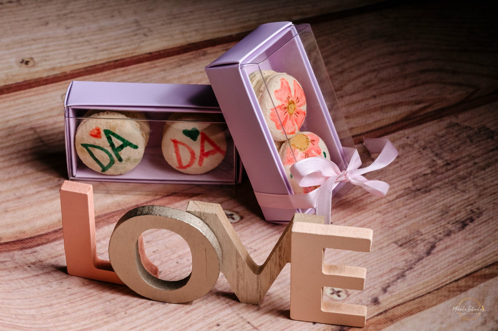 Cutii cu macarons personalizați ca mărturii de nuntă, cu mesajul "DA" și decor floral, lângă semnul "LOVE"