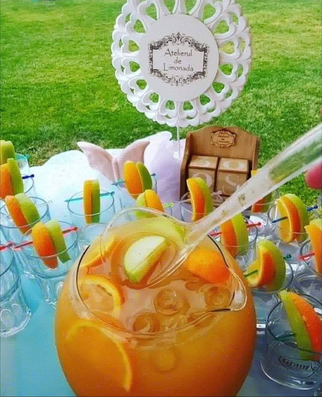 Bol cu punch răcoritor decorat cu felii de lămâie, portocală și măr verde, pregătit pentru servire la un eveniment organizat de Atelierul de Limonadă.