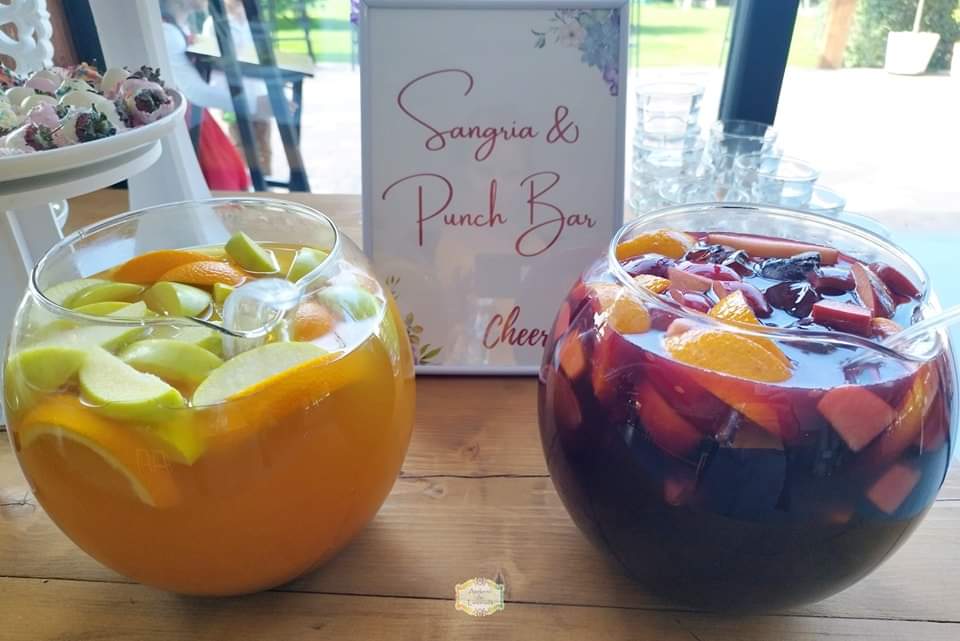Două boluri cu sangria și punch decorate cu felii de portocală, măr și gheață, pregătite pentru un bar festiv semnat Atelierul de Limonadă.