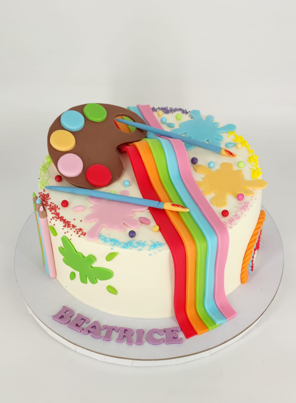 Tort de aniversare cu tematică artistică, personalizat cu numele Beatrice și decorat cu o paletă de pictor, pensule și un curcubeu de culori.